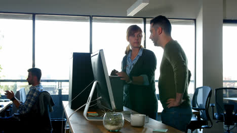 Executives-discussing-over-laptop-at-desk-4k