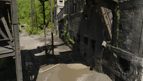 Leaking-sewage-drain-pipe-and-mud-puddles-in-abandoned-factory-ruins