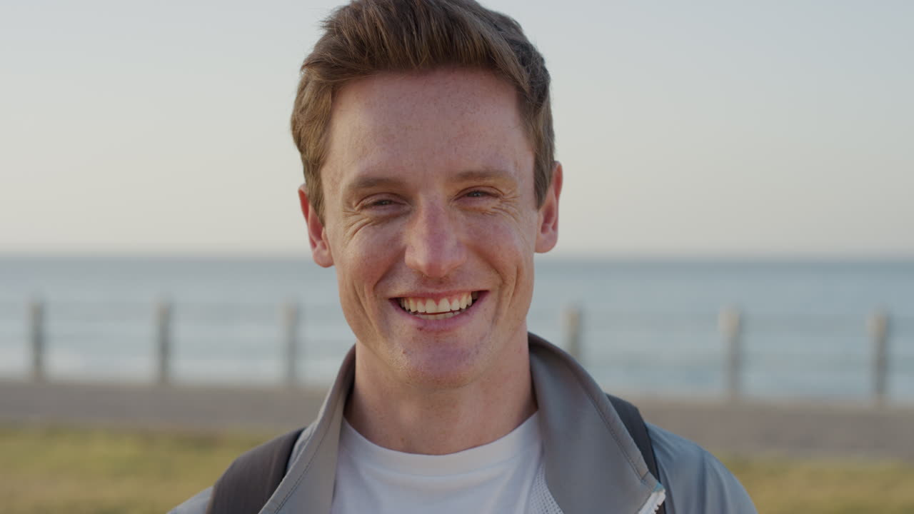 초상화 매력적인 젊은  ⁇ 은 머리 남자가 웃고 행복한 학생이 성공적인 라이프 스타일을 즐기고 따뜻한 여름날 바 ⁇ 가에서 휴식을 취하고 느린 동작