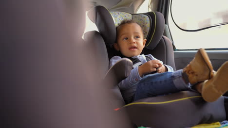 Little-mixed-race-boy-sitting-in-baby-seat,-talking-to-himself