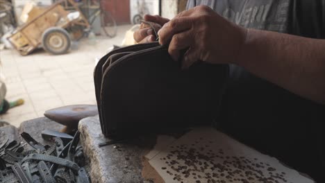 Artesano-De-Cuero-Cerrando-El-Bolso-De-Cuero-Después-De-Arreglarlo