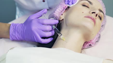 positive lady locating in cosmetology clinic for mesotherapy procedure. pretty woman getting beauty injection in neck.