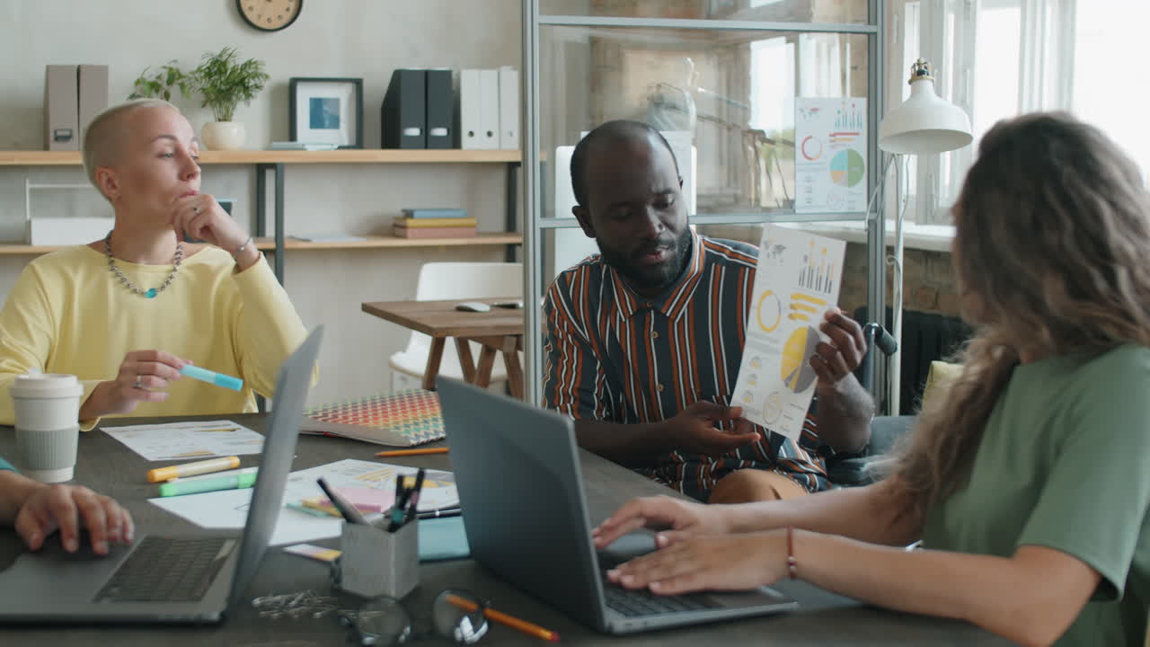 African American Man in Wheelchair Discussing Business Report with Team at Office Meeting