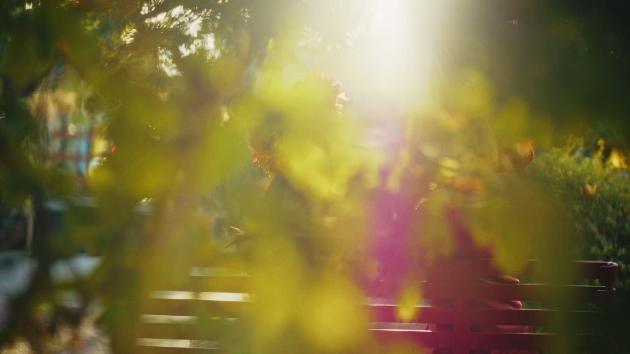 Woman sitting on a park bench, enjoying the sunlight and flowers.