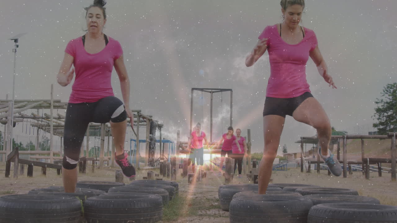 Women in pink shirts exercising on tires with cosmic animation overlay