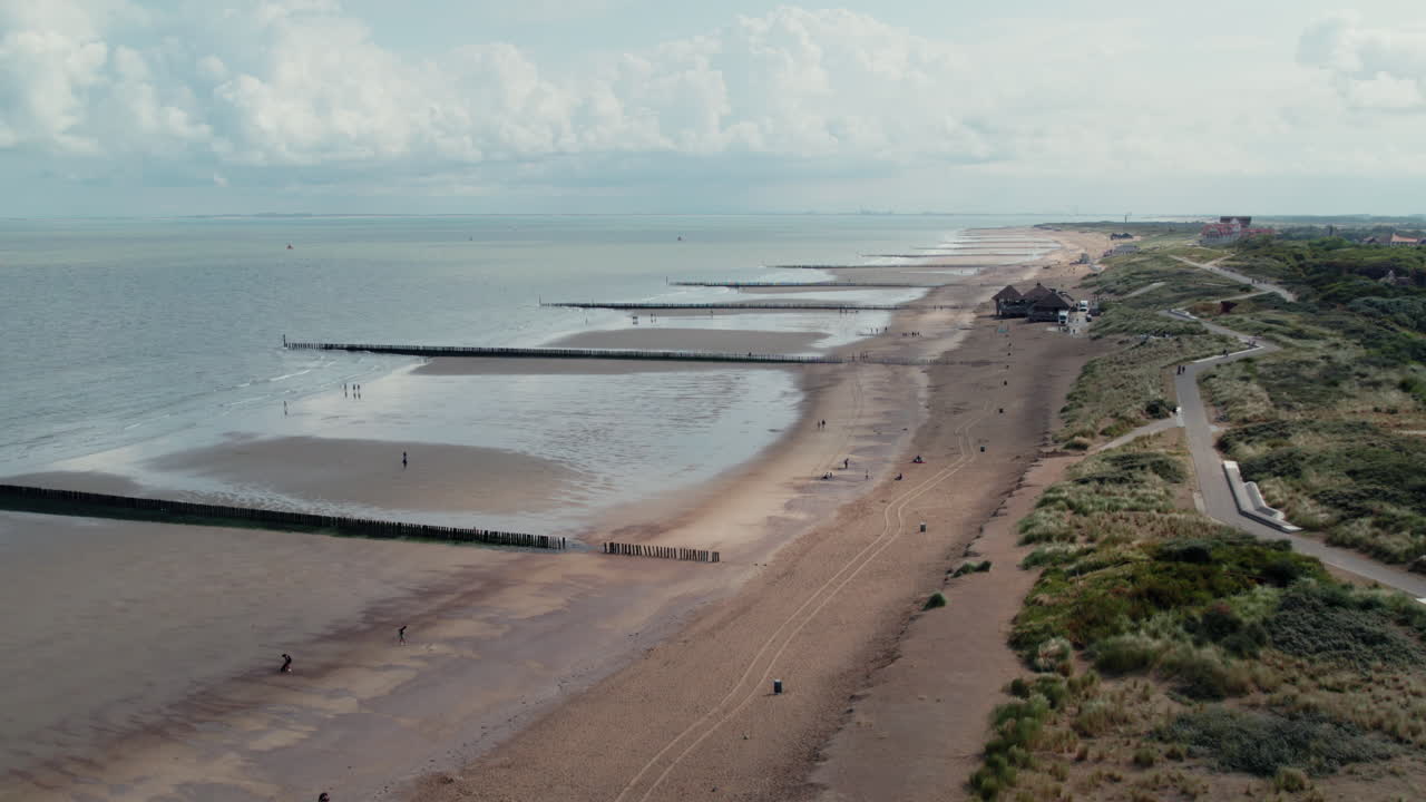 vista aérea de personas caminando por la playa con rompeolas en cadzand, zelanda, países bajos