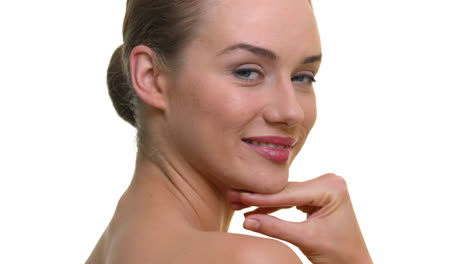 a close-up of a woman's face smiling and laughing, head tilting back with her hand brushing her face, on a seamless white studio background
