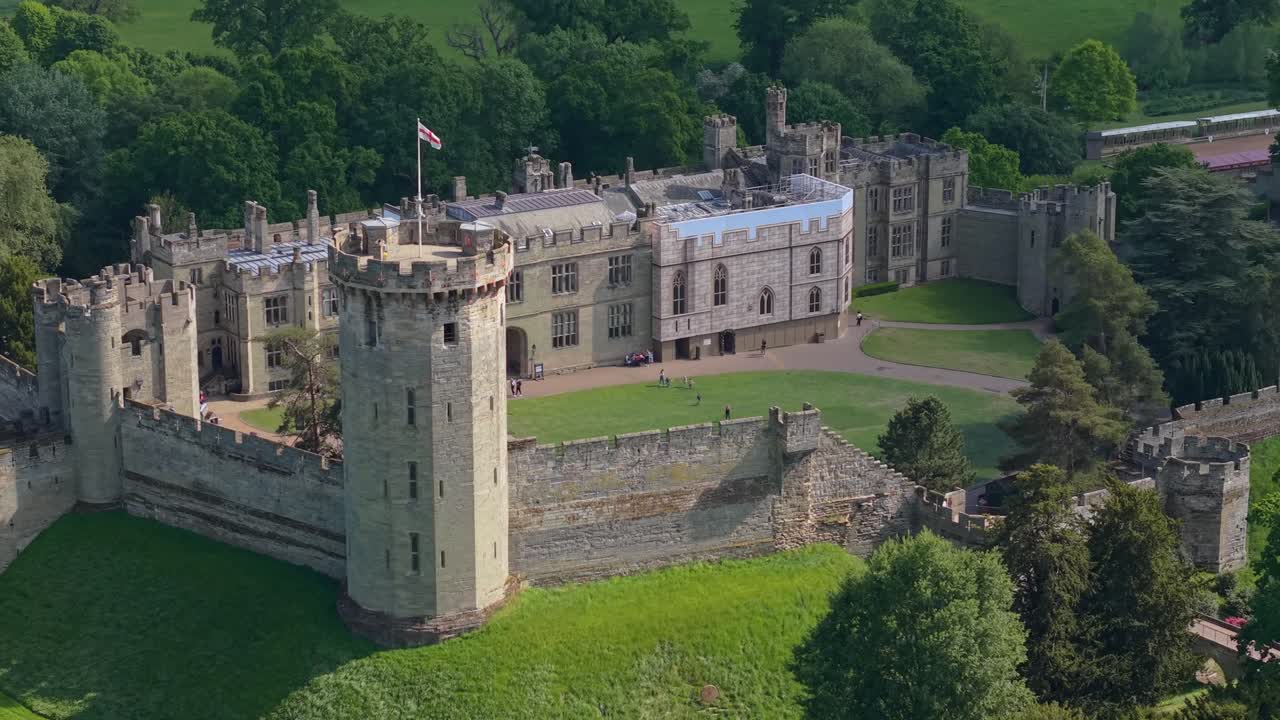Prise de vue latérale par drone du Donjon du Château de Warwick, révélant ses tours et le paysage pittoresque environnant avec son architecture médiévale et le charme de la campagne.