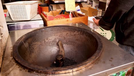 hombre asando granos de café en una sartén grande