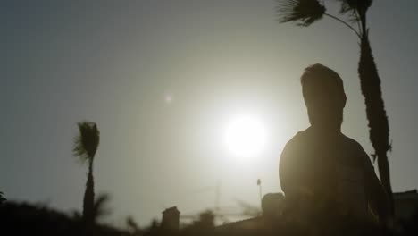 a man raking his garden, silhouetted against a bright sunny sky