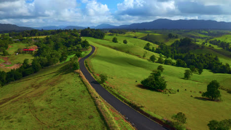 countryside landscape with scenic road and rolling hills in atherton tablelands, queensland, australia - aerial drone shot