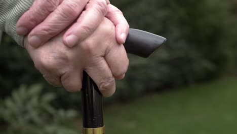 Elderly-lady-with-hands-on-a-walking-stick-close-up-shot