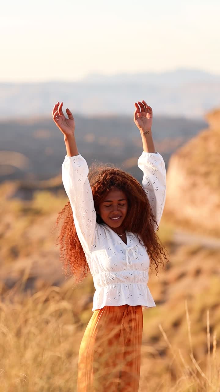 Young Woman with Curly Hair Enjoying Golden Hour in Nature