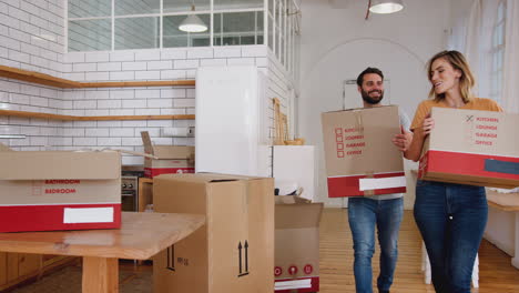 smiling young couple carrying boxes into new home on moving day