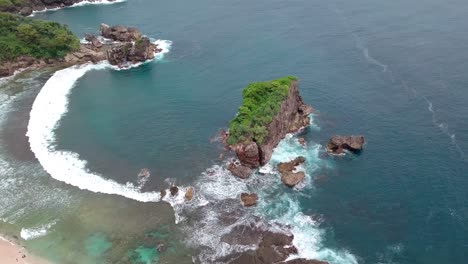 drone shot of coral rocks, the waves crashing rocks in the tropical ocean, aerial jungwok beach in gunung kidul regency, yogyakarta, indonesia