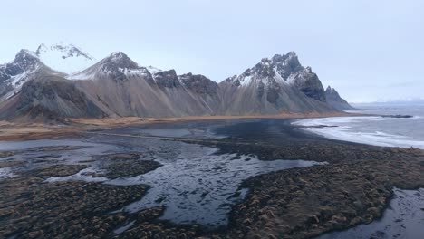 playa de arena del mar negro a la marea baja debajo de la montaña vestrahorn en islandia