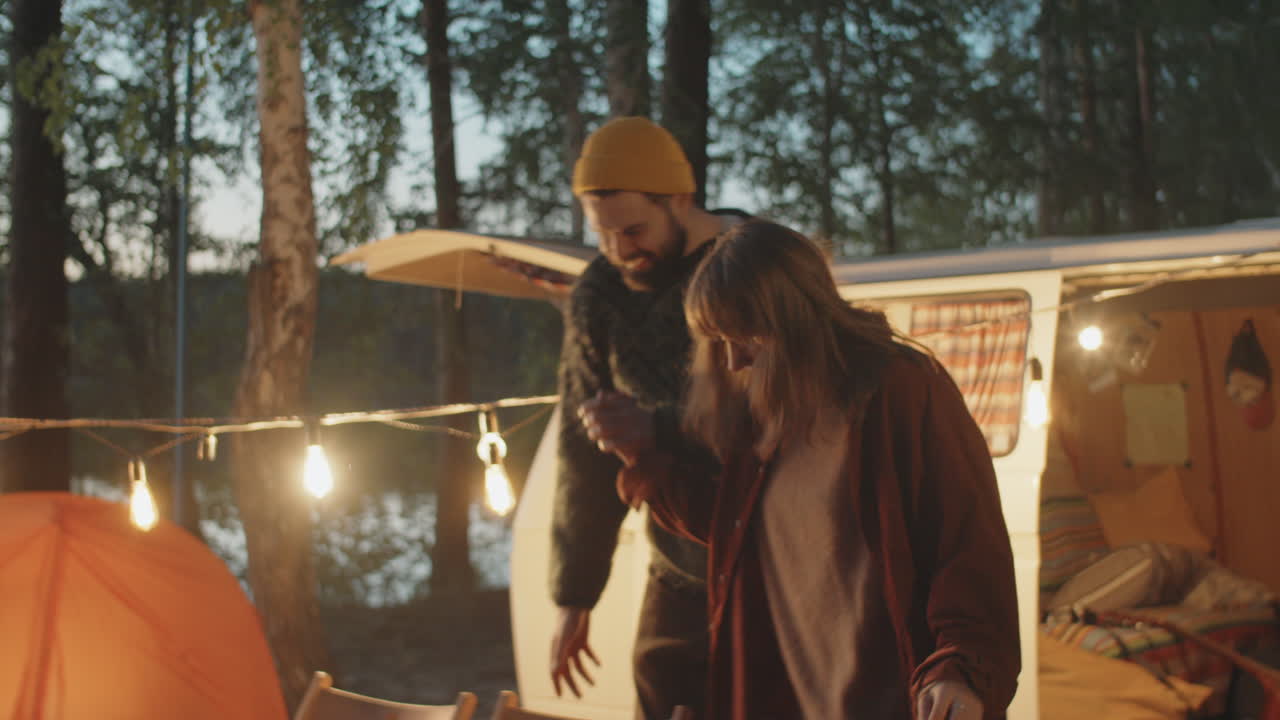 행복 한 부부 가 캠프 불 근처 에 앉아서 친해지고 이야기 하고 있다