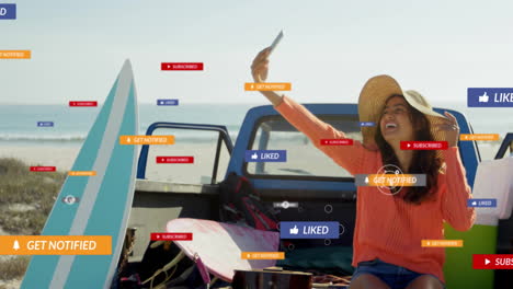 Taking selfie with social media notifications, woman in hat on beach