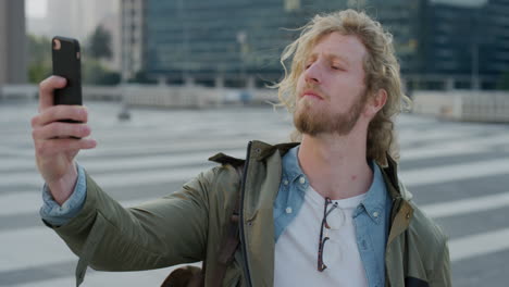 portrait young man tourist using smartphone taking selfie photo posing in city sharing vacation travel experience in urban background