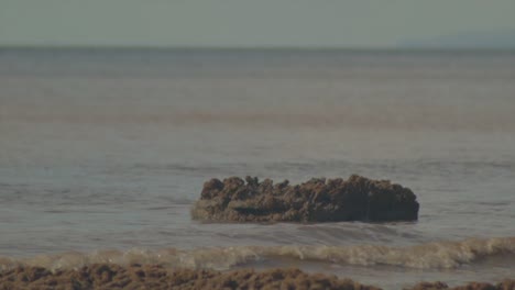 small wave breaking against a rock