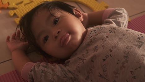 Sleepy-and-tired-Asian-baby-girl-lying-in-bed-and-looking-into-camera