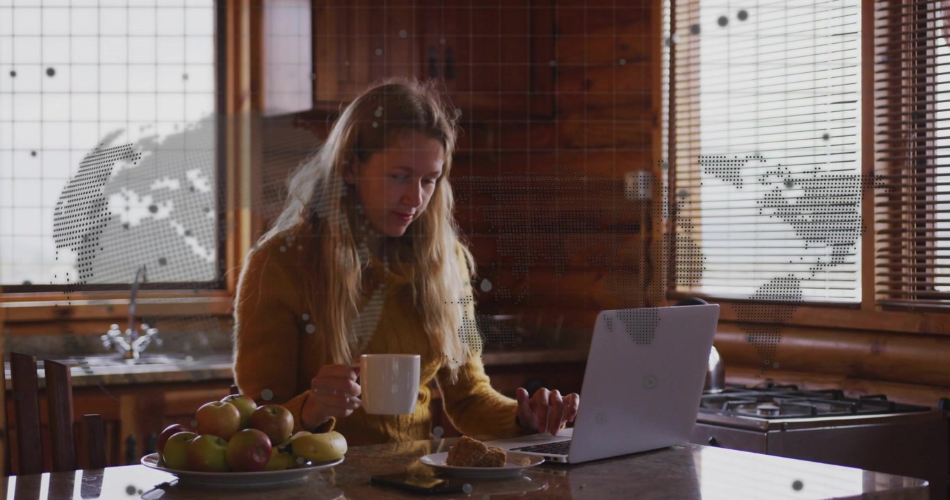 Junge Frau arbeitet am Laptop und trinkt Kaffee zu Hause mit globalem Netzwerk-Overlay.
