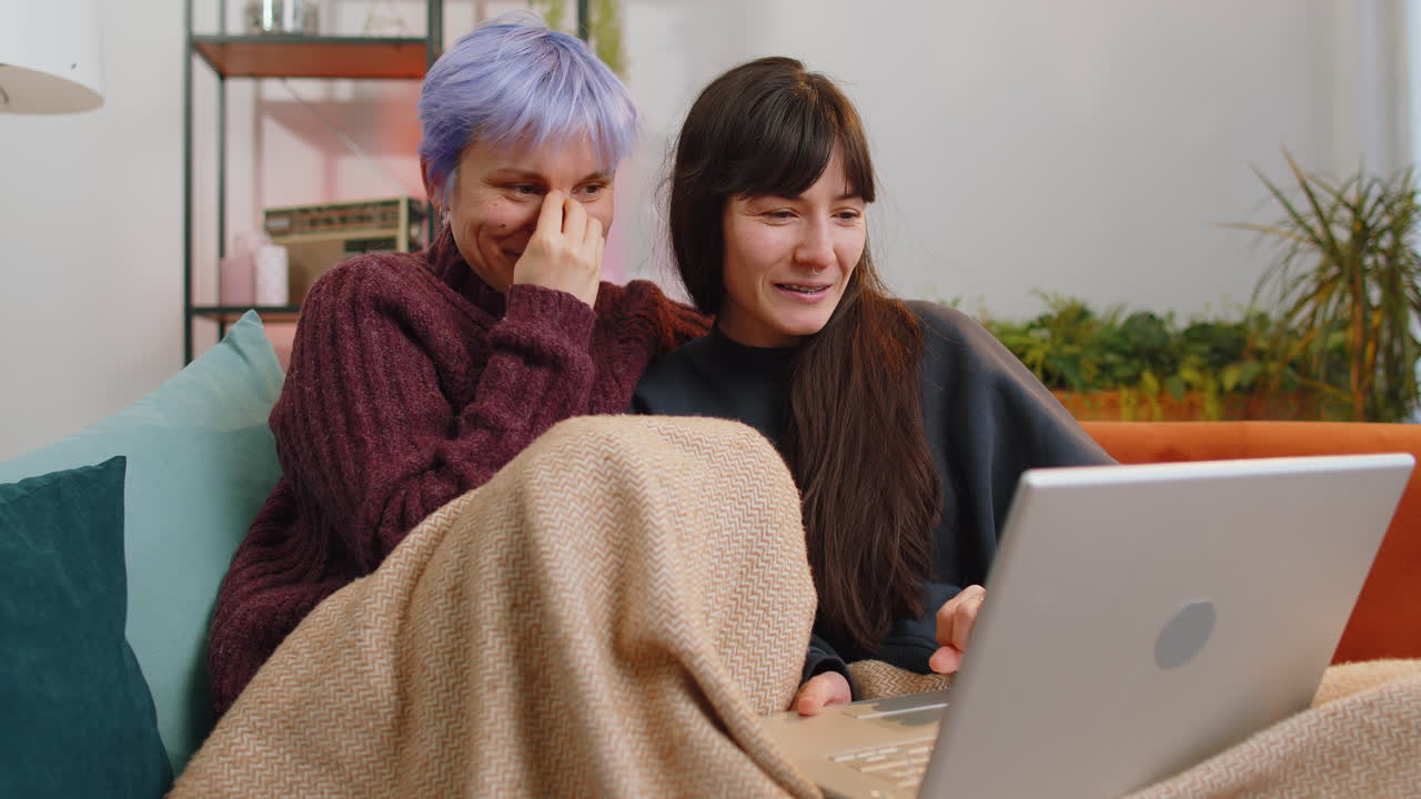 Lesbian women couple looking at laptop camera making video webcam conference call with family home