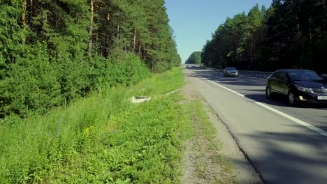 aerial ground level flying over the highway located in dense forest on the road passing cars and trucks