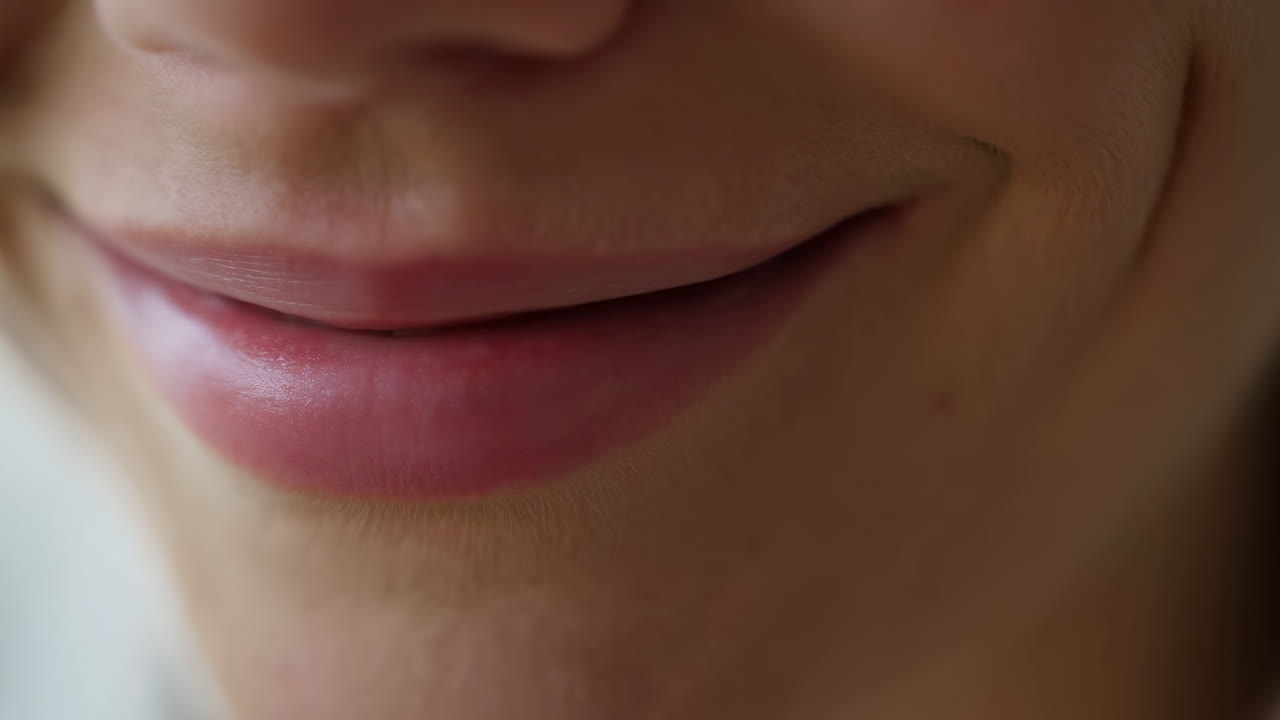 Primo piano di un sorriso sottile sulle labbra, luce naturale soffusa che rivela una texture della pelle liscia e delicate linee delle labbra, minimo