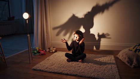 a child playing with shadow puppets on a wall illuminated by a lamp