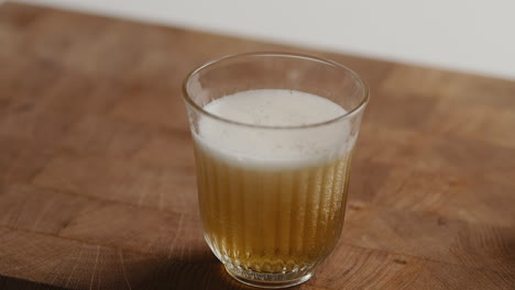 pouring beer from bottle into drinking glass at home in the kitchen