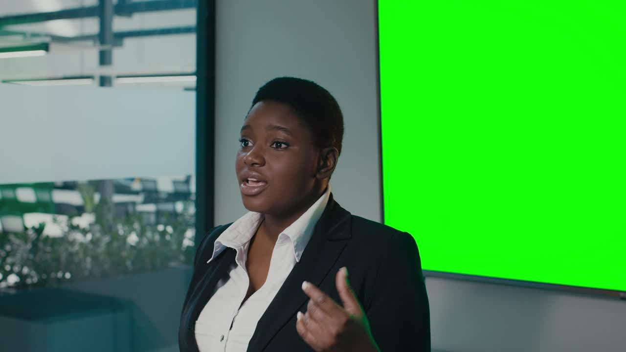 Confident Black Businesswoman Making Presentation In Office Near Green Chroma Key Screen