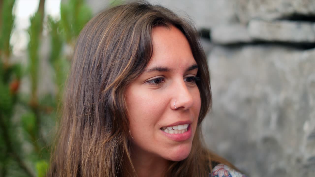 retrato de una mujer involucrada en una conversación, su cálida sonrisa y intrigante perforación de los labios