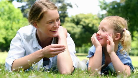 Glückliche-Mutter-Liegt-Mit-Ihrem-Kleinen-Mädchen-Im-Park-Auf-Dem-Gras