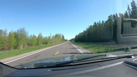 pov while driving on a narrow county road past golf course in rural northern minnesota in early spring on a bright day