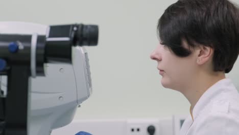 woman doctor is viewing through ophthalmoscope in eyes of patient in ophthalmologic clinic. professional inspection of vision