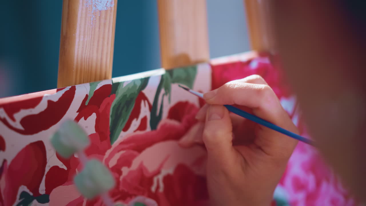 Artist Meticulously Crafts Floral Designs With Precise Brush Movements, Realistic Depiction Of Painter Carefully Illustrating Flower Patterns On Stretched Fabric Using Controlled Brush Strokes