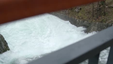 poderosa vista de la corriente de agua espumosa blanca a través de la barandilla del puente, pan a la izquierda