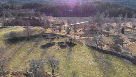 AERIAL---Farm-fields-and-stone-piles,-Smaland,-Sweden,-wide-shot-forward-descent