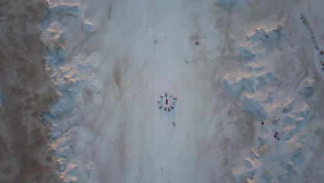 vista aérea giratoria de un campo de sal con un grupo de personas tendidas en el suelo formando un círculo en meditación