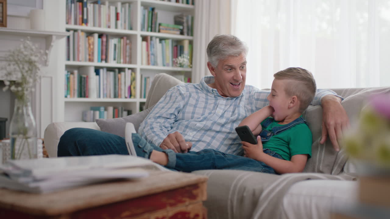 abuelo feliz mostrando al niño pequeño cómo usar el teléfono inteligente enseñando nieto curioso tecnología moderna niño inteligente aprendiendo teléfono móvil sentado con el abuelo en el sofá