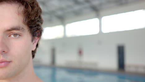 swimming in indoor pool, young man looking at camera with focused expression, copy space