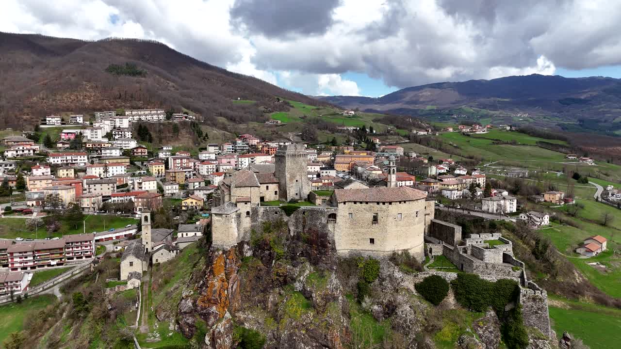 Aerial view of a castle in a town with mountains in the background