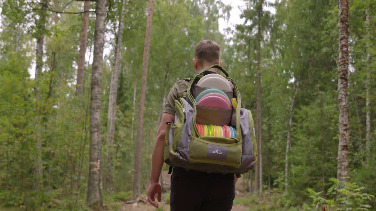 golfista de disco camina en un campo de golf de disco en el bosque - plano medio