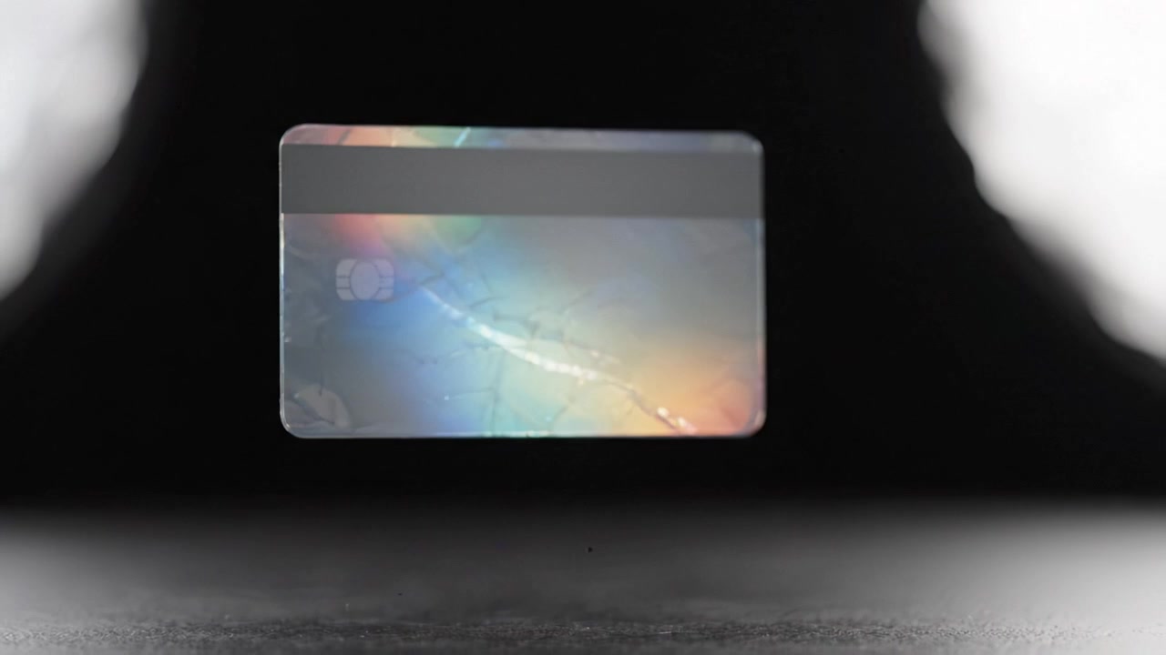 Una vista de cerca de una tarjeta de crédito destacando su superficie reflectante y diseño intrincado con un fondo borroso, mostrando su importancia en transacciones y finanzas.