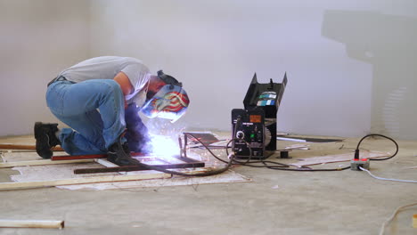 professional blacksmith welding steel frame with portable welding machine