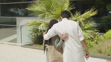 young muslim couple meeting in street, woman carrying shoppers.