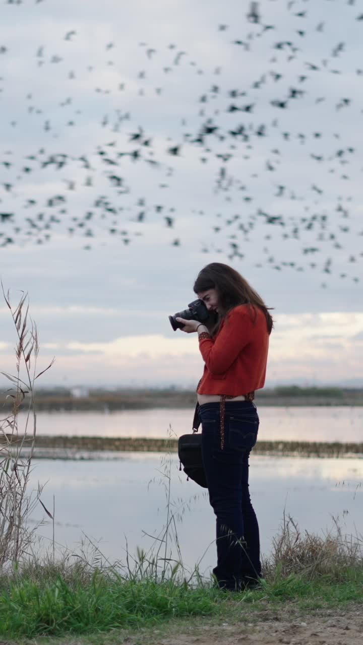Woman photographing birds by the lake
