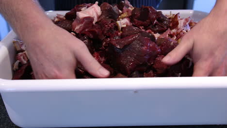 mixing meat in the white pan for sausage making to be served during meals - close up shot