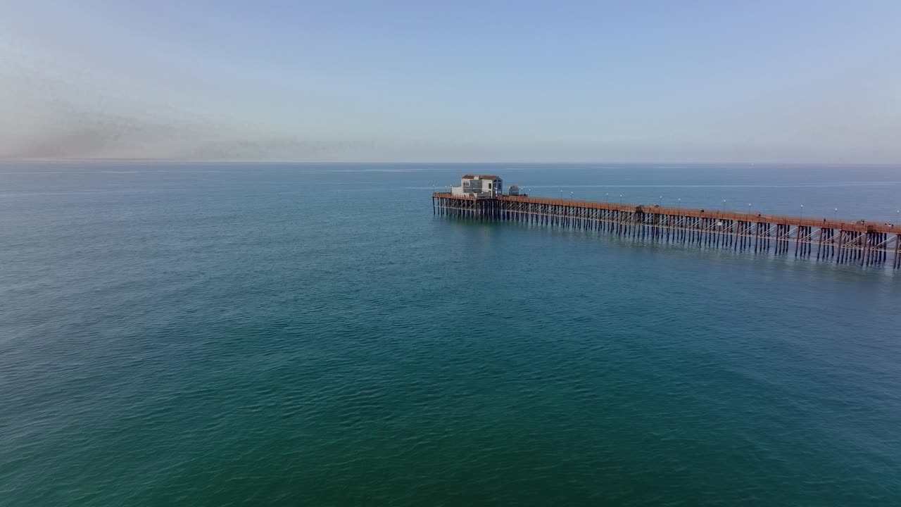 드론은 미국 남부 캘리포니아주 오션사이드에 있는 목재 부두를 향해 바닷물 위로 전진합니다.
